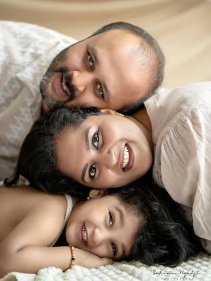 A creative and fun family portrait from an overhead angle. The family lies in a row, their happy faces creating a unique and memorable image.