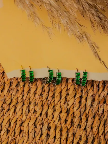 A row of vibrant green hoop earrings displayed on a woven surface. This shot highlights the product's bold color and is designed to grab attention in an online store.
