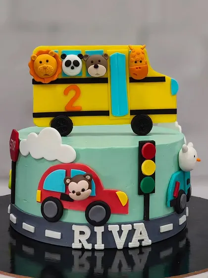 A full view of the adorable "Wheels on the Bus" themed cake. It’s a two-tier design that tells a little story, perfect for capturing a toddler's imagination.