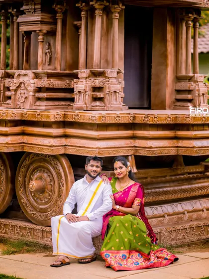 A classic portrait of a couple seated by a stone chariot, dressed in beautiful traditional outfits. This shot combines cultural heritage with romantic photography.