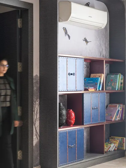 A shot of a woman walking through a study area with custom puzzle-like shelving. This image captures the interactive and unique design elements we incorporate into our projects.