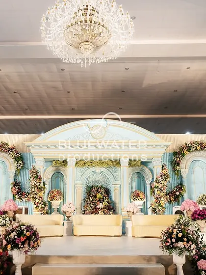 A frontal view of the 'Blue Palace' stage, highlighting the detailed architectural elements, the balance of powder blue and white, and the abundant florals that add softness and color.