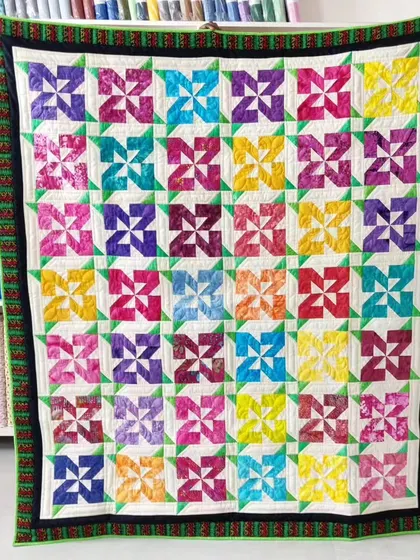 A vibrant "Pinwheel" quilt using a rainbow of colors, with a fun, scrappy border.