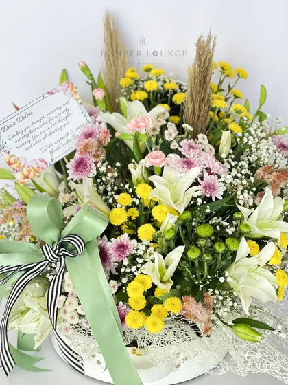 A closer look at the "Get Well Soon" bouquet. The combination of white lilies, yellow chrysanthemums, and delicate greenery creates a fresh and uplifting arrangement to lift someone's spirits.
