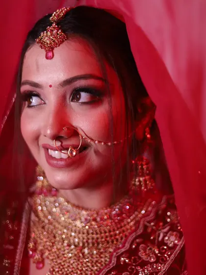 A candid, smiling portrait of the bride looking away. The soft red lighting creates a warm and romantic atmosphere.
