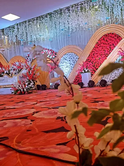 A different perspective of the grand reception stage with a red floral carpet and elaborate backdrop.