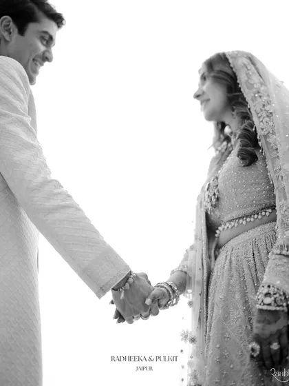 A black and white shot of the couple holding hands, a simple and timeless gesture of love and commitment from their Jaipur wedding.