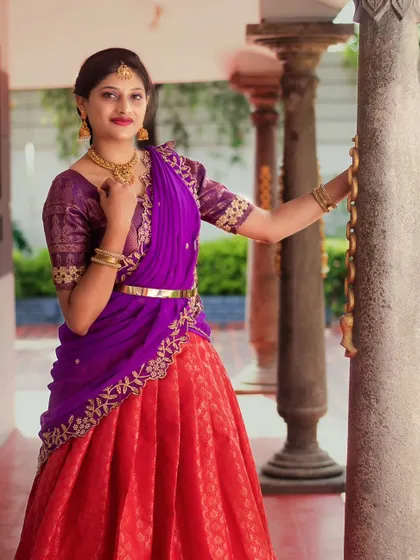 A client looking graceful in a traditional red and purple half-saree, perfect for a festive occasion.