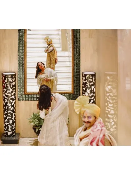 A creative and artistic shot using reflections. The groom waits while the bride is captured in multiple reflections, creating a layered and interesting composition.