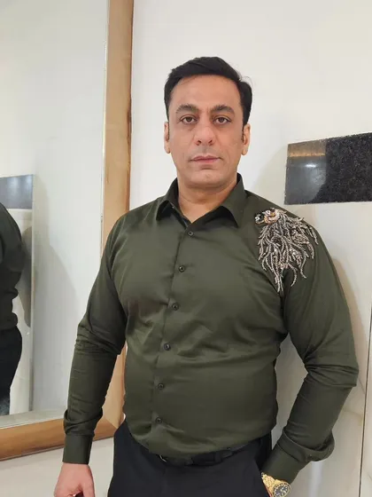 A client wearing a custom olive green shirt with embroidery on the shoulder. Even for casual wear, we can add a touch of bespoke detail to make your piece unique.