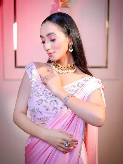 A soft and elegant portrait in a pink saree, using gentle pink-toned lighting to complement the outfit.