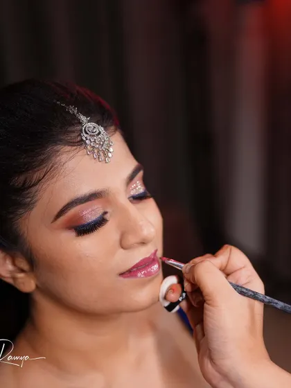 Applying lip color for Meghana's reception look. The glittery eye makeup and diamond jewelry create a perfect party-ready style.
