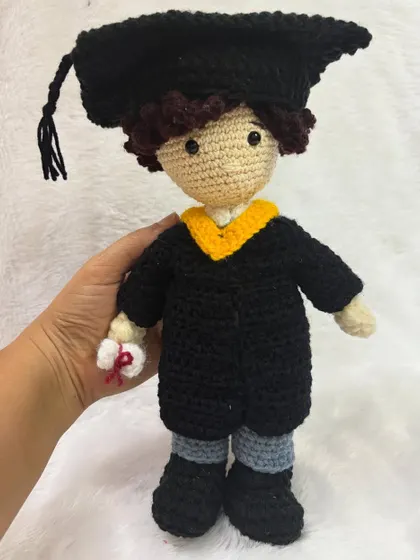 Holding the graduation doll to show its size. It's a thoughtful and unique gift that commemorates a major milestone.