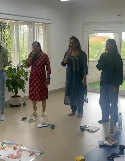A group of educators practices the action for the 'sh' sound during our phonics training. By embodying the sounds, teachers gain a deeper understanding and are better equipped to teach them with confidence.
