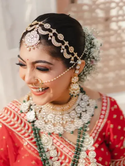 A close-up of the bride's joyful smile, highlighting her intricate matha patti and stunning jewellery. Her happiness is infectious, a perfect capture of bridal bliss.