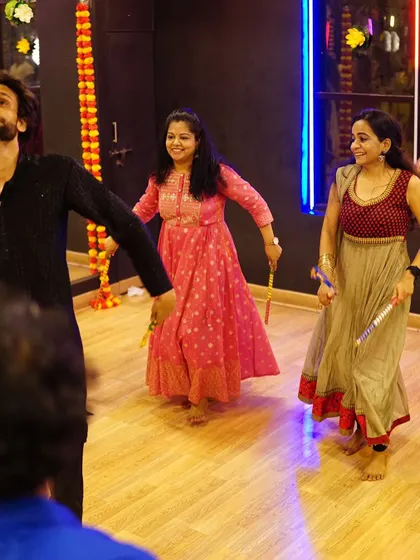 Our instructor leading a Dandiya session, with participants smiling and following along. We guide your family and friends through every step.