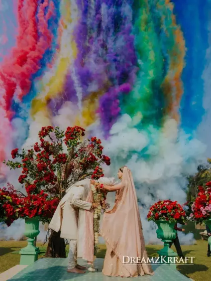 A varmala moment that feels like a painting. We used a burst of colorful smoke to create a dramatic and joyful backdrop, celebrating the couple's union in a vibrant, unforgettable way.
