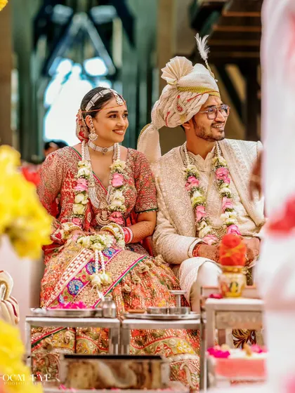A candid shot of the bride and groom seated at the mandap, sharing a smile during the wedding rituals.