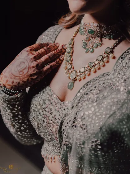 A close-up detail shot of the bride's stunning jewelry and the intricate work on her cocktail lehenga.