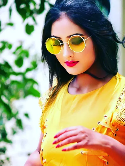 A bright and modern look perfect for a summer photoshoot. The makeup features a clean base, a pop of red on the lips, and is styled with trendy yellow sunglasses and a matching top.