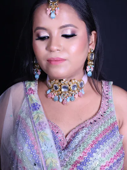 A happy client ready for her engagement in a pastel multi-color lehenga. The intricate beadwork and soft colors make it a perfect choice for a day function.