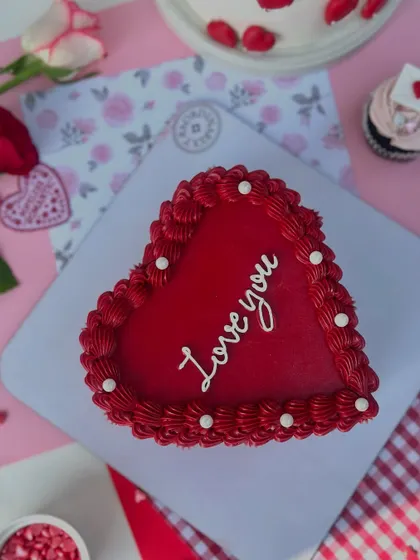 A top-down view of the red heart-shaped "Love you" cake, showcasing its rich color and delicate piping.