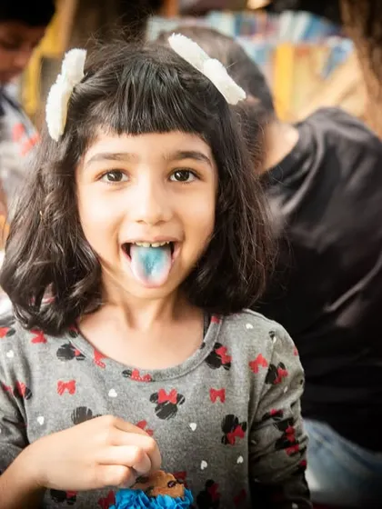 Birthday party fun. This candid shot captures a girl's playful side, sticking out her blue tongue for the camera.