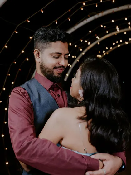 We create intimate and romantic settings for our couple shoots. This photo captures a loving gaze between a couple, surrounded by the warm, soft glow of an archway decorated with fairy lights.