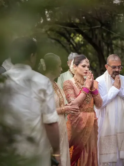 A quiet moment of prayer for the bride, framed through the leaves. This candid shot captures her faith and the peaceful moments before the wedding ceremony.