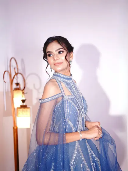 A side profile in the blue gown, highlighting the elegant updo and delicate earrings that pair perfectly with it.