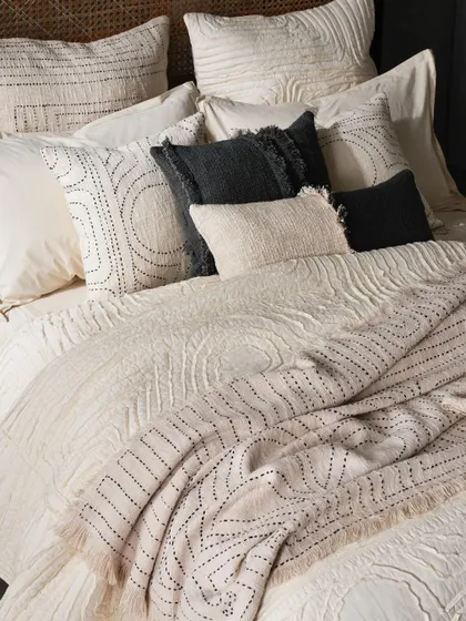 A close-up on layered bedding, emphasizing the rich textures and hand-stitched details. This type of shot is crucial for showing product quality and craftsmanship in home textile photography.