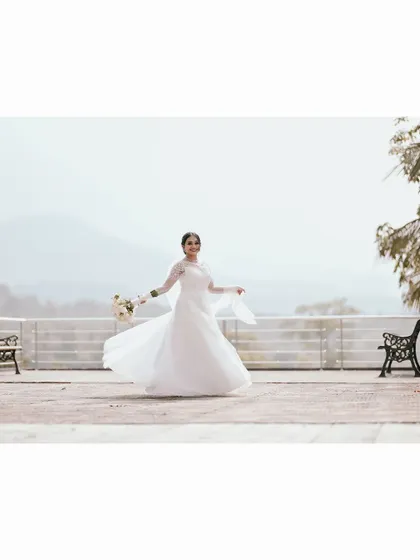 A happy, twirling shot of the bride on a balcony, her white dress flowing against a scenic mountain backdrop.