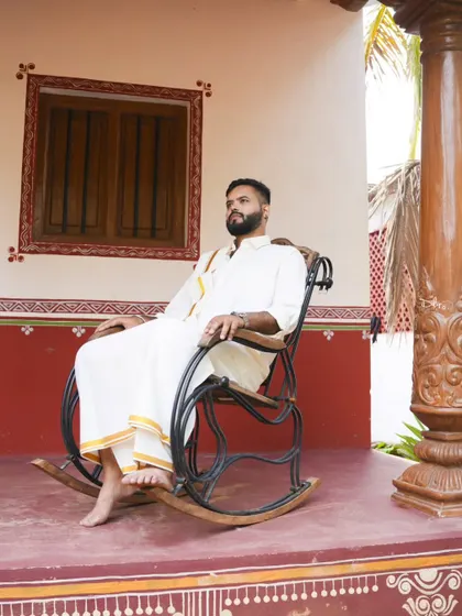 A portrait of the groom-to-be in traditional attire, relaxing in a rocking chair on a veranda. This captures a quiet, classic moment.
