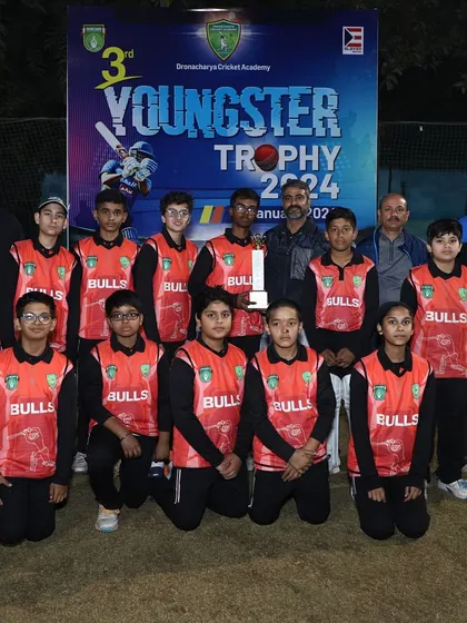 A young girls' team, the DCA Bulls, proudly posing with their trophy at the Youngster Trophy 2024, highlighting our commitment to promoting women's cricket.