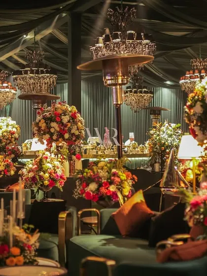 This wide shot captures the full scope of the floral arrangements and lounge seating. The strategic placement of heaters ensures guest comfort during an outdoor evening event without compromising on style.