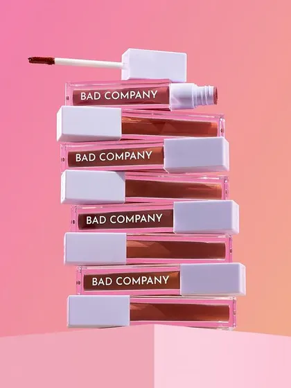 A hero stack of "Bad Company" liquid lipsticks against a vibrant gradient background. Stacking the products creates a strong focal point and showcases the full product line in a visually interesting way.