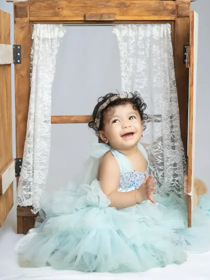 Peeking out from a window prop, this little one's joyful expression is contagious. Props can add a fun, interactive element to milestone shoots.