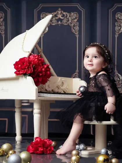Posing like a pro! This little one is enjoying her glamorous first birthday shoot by the piano.