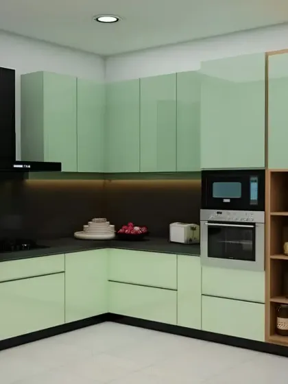 A modern L-shaped kitchen in a soft sage green. The design includes a tall unit with open shelving for spices and jars, adding a practical touch.