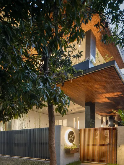 The entrance at dusk, with the lighting emphasizing the texture of the wood-clad portico and the concrete wall.