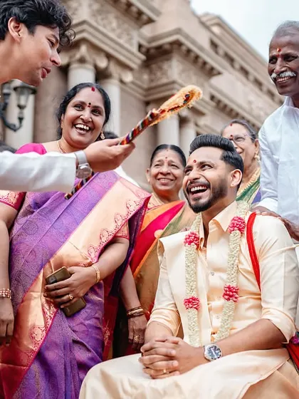 A candid shot of a groom laughing as he is blessed by family during a wedding ritual. We capture the happy moments of everyone involved.
