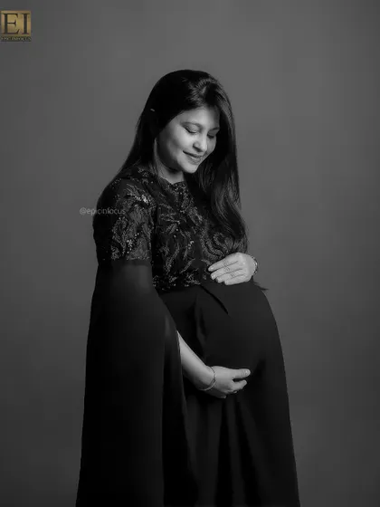 A gentle and introspective black and white portrait of the mom-to-be looking down at her bump.