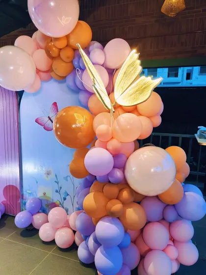 A close-up of a light-up butterfly prop placed within a colorful balloon arrangement. This small detail adds a touch of magic and light to the decor.