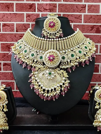 This grand rental set features a heavy choker and matching jhumkas with intricate kundan and beadwork. The combination of green and magenta makes it a vibrant choice.
