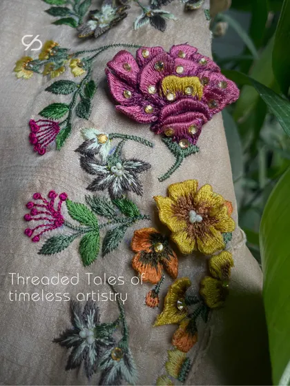 Threaded tales of timeless artistry. Soft touches of 3D embroidery and beadwork grace the fabric, creating a delicate and textured floral design.