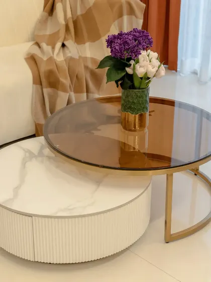 A detail shot of the nesting coffee table, which combines a marble-finish base with a tinted glass top, adding a touch of modern sophistication.