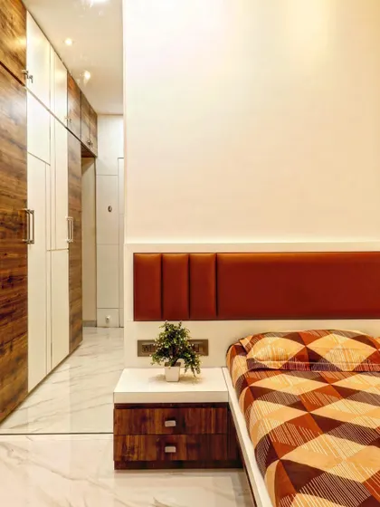 A detail view of a bedroom showing the seamless integration of the wardrobe with the rest of the room. The combination of white and wood laminate on the wardrobe doors adds warmth and modernity.