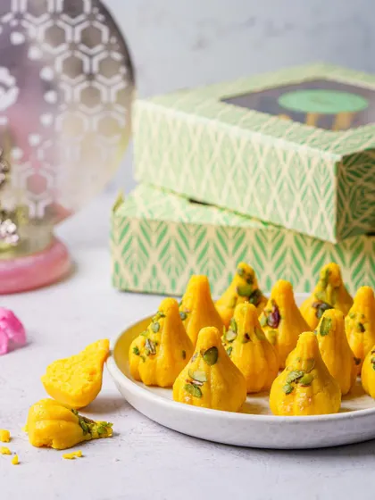 A platter of yellow modaks with pistachio garnish. Our festive photography focuses on creating a celebratory and auspicious mood that aligns with the spirit of the festival.