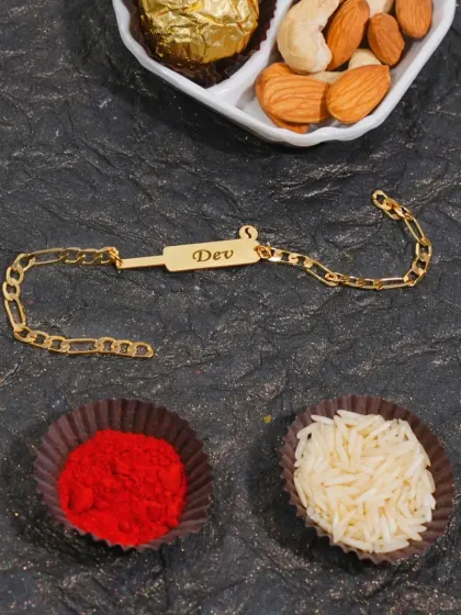 A modern, chain-style rakhi bracelet with a simple nameplate. It comes with traditional roli and chawal for the ceremony.