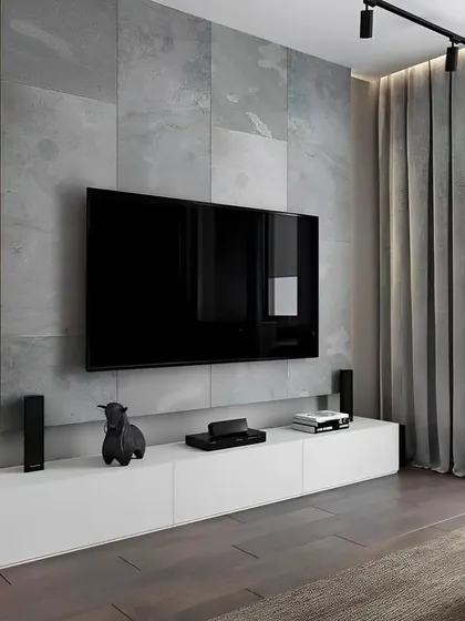 This minimalist living room features a simple white floating console against a grey tiled accent wall. A single track light and vertical LED strip provide focused, modern illumination.